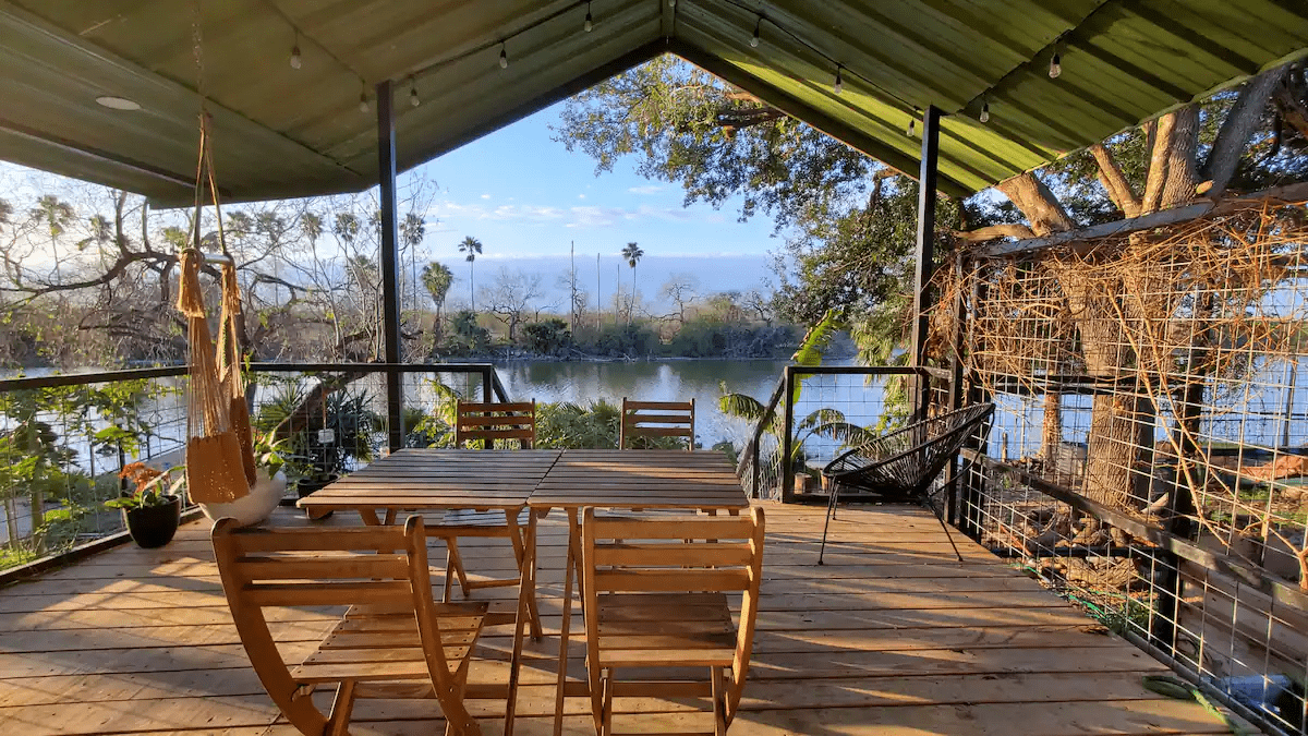 a poarch with picnic tables and chairs with a view of a lake